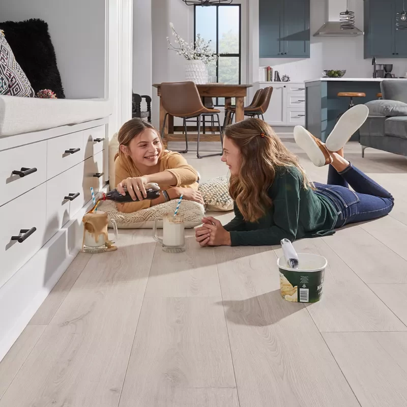 Choosing-Laminate Two Teens Layin on Laminate Flooring Eating Snacks | Ambassador Flooring